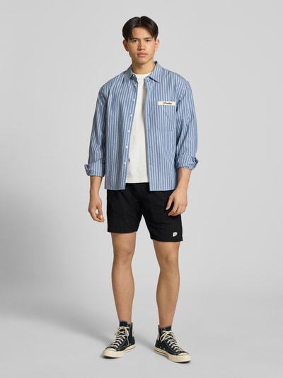 Männermodel trägt Shorts mit Label-Patch Modell 'LIBCO' von Pegador, schwarzer Farbton, Strukturmuster, Material-Mix, Gerader-Schnitt, elastischer Bund, Ganzkörperansicht von vorne. Kontext: Herren Shorts von Pegador, elastischer Bund, Bundweite bei Größe M 38 cm, Innenbeinlänge bei Größe M 23 cm.