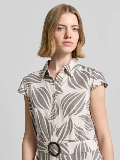 Frauenmodel trägt Midikleid aus Viskose-Mix mit Leinen-Anteil von Apricot, florales Allover-Muster in Beige und Grau, Nahaufnahme Oberkörper. Leicht taillierte Passform mit Umlegekragen, kurzer Ärmellänge, Stoffgürtel und durchgängiger Knopfleiste.