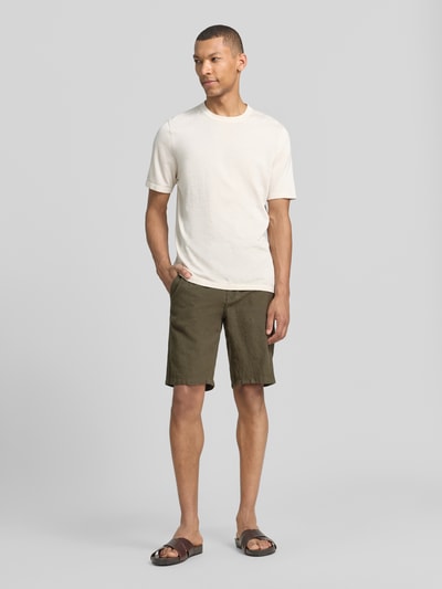 Männermodel trägt Bermudas aus Leinen-Mix mit französischen Eingrifftaschen von Lindbergh in Olivgrün, Straight Fit, elastischer Bund mit Kordelzug, Knopf- und Reißverschluss, Bundweite 43 cm, Innenbeinlänge 24 cm, Ganzkörperansicht von vorne.
