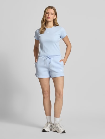 Frauenmodel trägt Cropped T-Shirt in Ripp-Optik mit Logo von Nike aus Baumwoll-Elasthan-Mix, Rundhalsausschnitt, hellblau, Ganzkörperansicht von vorne. Rückenlänge bei Größe S: 49 cm.