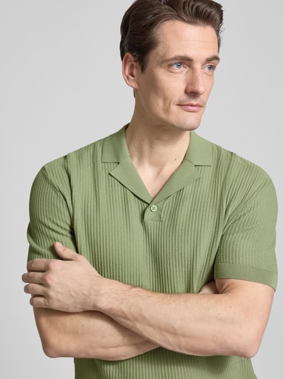 Männermodel trägt Regular Fit Poloshirt mit Reverskragen und V-Ausschnitt von Armani Exchange aus reine Baumwolle, Nahaufnahme Oberkörper.