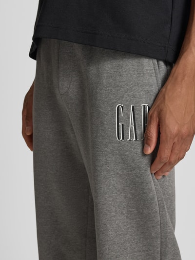 Männermodel trägt Sweatpants mit elastischem Bund und Logo von GAP aus Baumwoll-Mix, Regular-Fit, graue Farbe, Nahaufnahme Oberschenkel.