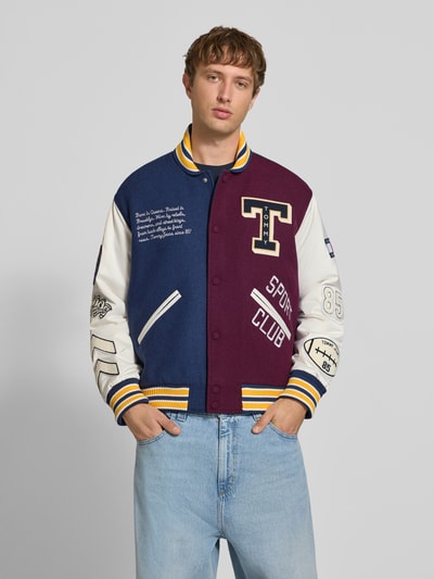 Männermodel trägt Regular Fit Bomberjacke aus Woll-Mix Modell 'LETTERMAN' von Tommy Jeans in Dunkelblau, Bordeaux und Weiß, Nahaufnahme Oberkörper. Kontext: Herren Bomberjacke / Blouson von Tommy Jeans.
