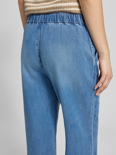 Frauenmodel trägt Wide Leg Jeans aus Lyocell Modell 'GRETA' von Only in Denim-Optik, High-Waist-Stil, elastischer Bund mit Tunnelzug, seitliche Eingrifftaschen, Material Lyocell, Ganzkörperansicht Rückansicht.