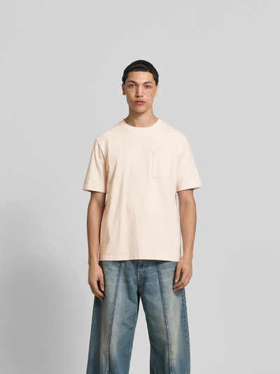 Männermodel trägt Relaxed Fit T-Shirt mit Brusttasche von MAISON KITSUNÉ aus reiner Baumwolle mit Logo-Print, Rundhalsausschnitt, Ganzkörperansicht von vorne.