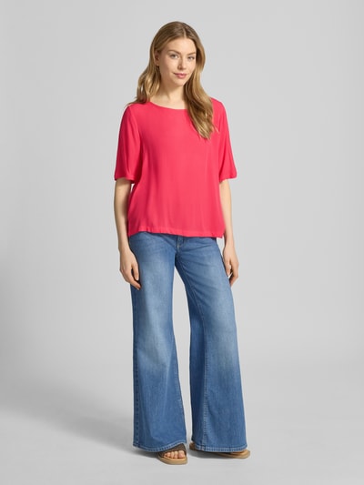 Frauenmodel trägt Relaxed Fit T-Shirt aus reiner Viskose Modell 'Marrakech' von ICHI, leuchtendes Pink, kombiniert mit Jeans, Ganzkörperansicht von vorne. Damen T-Shirt, Rundhalsausschnitt, Rückenlänge 58 cm, Ärmellänge 29 cm.