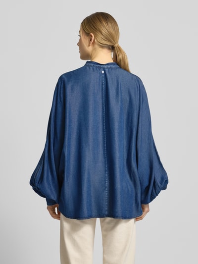 Frauenmodel trägt Oversized Jeansbluse aus Lyocell Modell 'C_BETTA' von BOSS Orange w stylu denim, krój oversized, stójka, na całej długości listwa guzikowa, aplikacja z metką, rękawy nietoperzowe, zakończenie rękawów mankiet, materiał lyocell, kolor niebieski, gładka tekstura. Ganzkörperansicht Rückansicht.