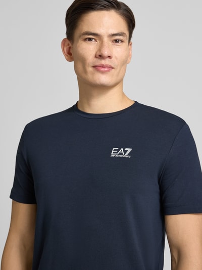 Männermodel draagt T-Shirt met Label-Print van EA7 Emporio Armani, donkerblauw, slim fit, katoenen mix, nahaufnahme bovenlichaam.