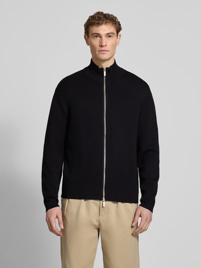 Männermodel trägt Relaxed Fit Strickjacke aus Viskose-Mix Modell 'TELLER' von SELECTED HOMME, unifarben schwarz, Reißverschluss, Ganzkörperansicht von vorne.
