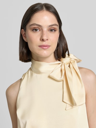 Frauenmodel trägt Blusentop mit Schluppe Modell 'Veda' von Neo Noir aus Satin in Creme, Gerader-Schnitt, Stehkragen, Nahaufnahme Oberkörper.