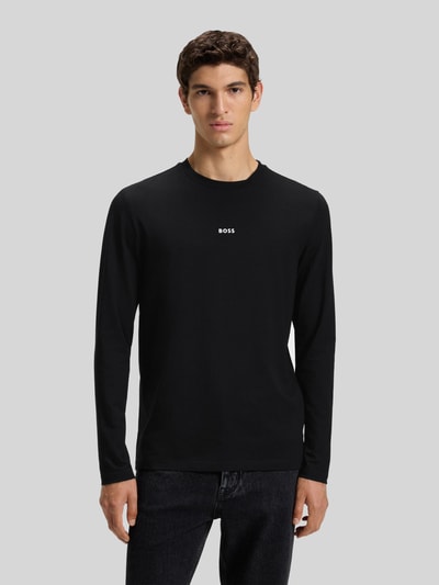 Mężczyzna nosi Regular Fit Langarmshirt aus Baumwoll-Mix Modell 'TCHARK' od BOSS Orange, czarny, jednolity, nadruk z logo, okrągły dekolt, krój regular fit, długi rękaw, widok całościowy z przodu.