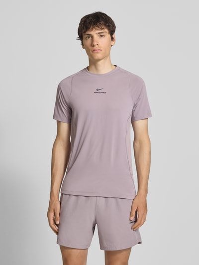 Männermodel trägt T-Shirt mit Logo-Print und Raglanärmeln von NIKE TRAINING in Flieder, Straight Fit, Rundhalsausschnitt, Ganzkörperansicht von vorne, Rückenlänge bei Größe M 71 cm.