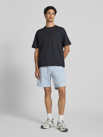 Männermodel trägt Regular Fit Shorts mit Logo-Stitching von Pegador aus Baumwoll-Mix in Hellblau, elastischer Bund, Ganzkörperansicht von vorne.