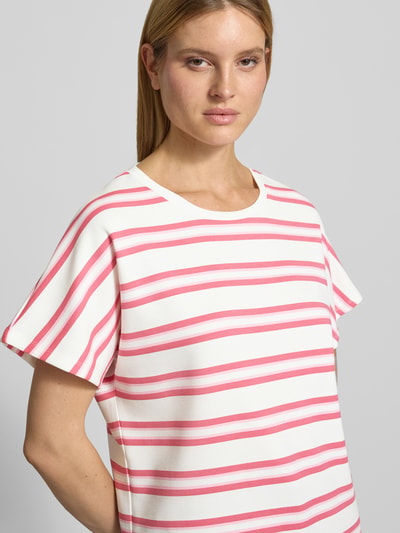 Kobiece model nosi damski t-shirt z mieszanki materiałów z domieszką modalu od Soyaconcept, model 'BARNI', okrągły dekolt, krój relaxed fit, biały z różowymi poziomymi paskami; zbliżenie na górną część tułowia z przodu.