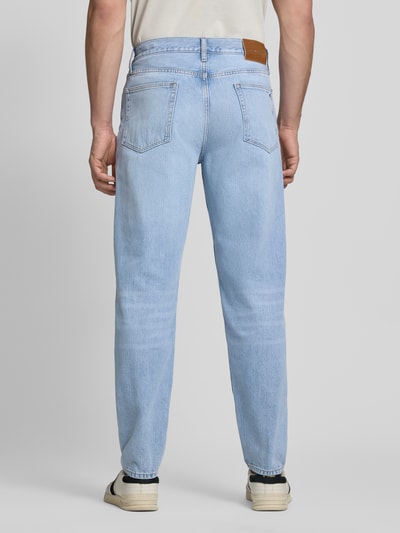 Männermodel trägt Tapered-Fit Jeans aus reiner Baumwolle Modell 'HARLEM' von Tommy Hilfiger in Denim-Optik mit Label-Patch und Nieten, Ganzkörperansicht Rückansicht.