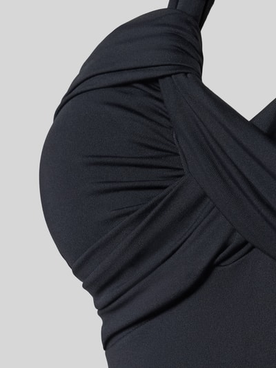 Frauenmodel trägt Body mit Neckholder von Seafolly in Schwarz, Raffungen, Material-Mix mit Stretch-Anteil, Nahaufnahme Oberkörper.