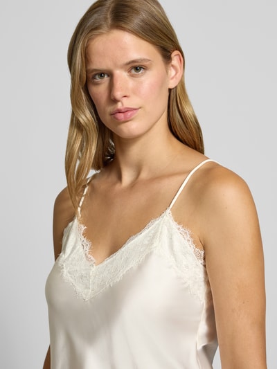 Frauenmodel trägt Regular Fit Top aus Satin mit Spitzenbesatz von REVIEW in Creme, glatte Textur, Spaghetti-Träger, Nahaufnahme Oberkörper.