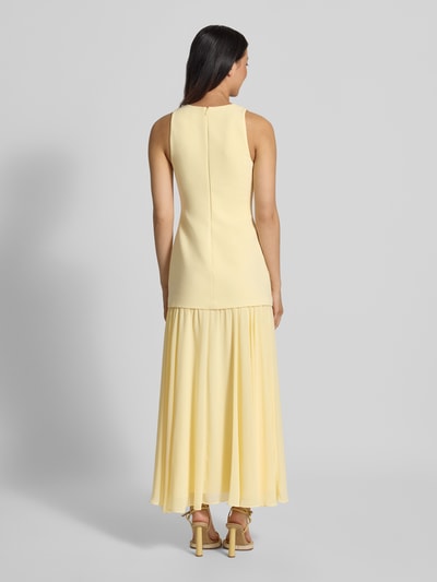Vrouwenmodel draagt avondjurk met viscose van Forever New, nauwsluitend model Melva, vierkante hals, mouwloos, chiffon rok, maxilengte, elastische materiaalmix, rugritssluiting, ruglengte 137 cm, borstwijdte 37 cm, geheel gele kleur, gladde en lichte textuur, volledige lichaam achteraanzicht.
