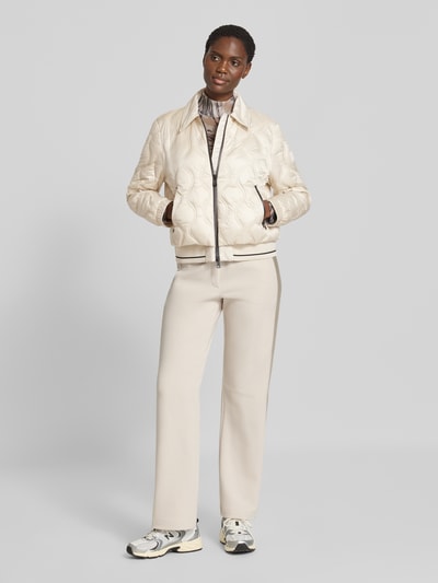 Frauenmodel trägt Steppjacke mit Umlegekragen und Reißverschlusstaschen von Marc Cain in Creme, Regular Fit, strukturierte Oberfläche, Ganzkörperansicht von vorne.