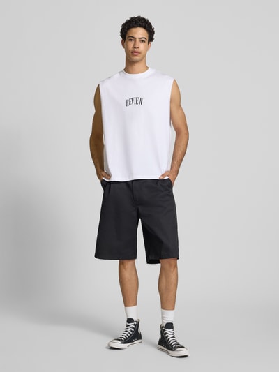 Männermodel trägt Muskelshirt mit Logo und Rundhalsausschnitt von REVIEW aus reiner Baumwolle im Regular Fit in Weiß, Ganzkörperansicht von vorne.