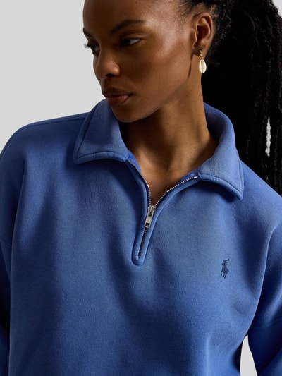 Frauenmodel trägt Sweatshirt mit Label-Stitching von Polo Ralph Lauren in Blau mit Polokragen und Reißverschluss, Nahaufnahme Oberkörper.