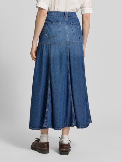 Frauenmodel trägt Maxirock aus Lyocell-Mix in Denim-Optik Modell 'Nidia' von Guess, blaue A-Linie, 5-Pocket, Rückansicht Ganzkörperansicht.