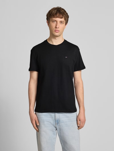Männermodel trägt Regular Fit T-Shirt aus reiner Baumwolle von Tommy Jeans, Optik: Unifarben, Logo-Stitching, Ganzkörperansicht von vorne.