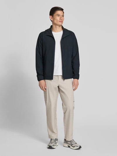 Männermodel trägt Regular Fit Jacke mit Kapuze von SCANDINAVIAN EDITION, dunkel, glatte Textur, Zweiwege-Reißverschluss, Ganzkörperansicht von vorne.