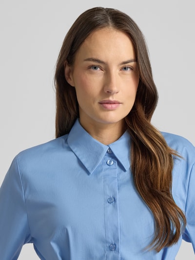 Frauenmodel trägt Hemdbluse aus Baumwoll-Mix Modell 'Zopy' von Gestuz in Hellblau mit Knopfleiste, Nahaufnahme Oberkörper. Taillierte Passform, Hemdblusenkragen, Langärmelig, Sportmanschetten, Rückenlänge 68 cm, Ärmellänge 63 cm bei Größe 36, glatte Textur.
