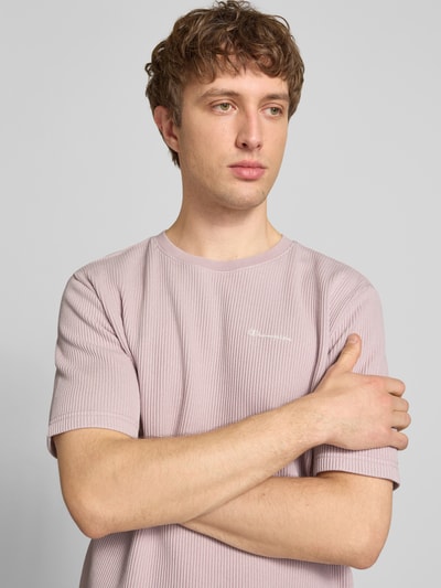 Männermodel trägt T-Shirt mit Strukturmuster und Label-Stitchings von CHAMPION, Baumwoll-Mix in zartem Rosa, Nahaufnahme Oberkörper.