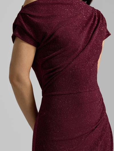 Frauenmodel trägt Cocktailkleid mit One-Shoulder-Träger von Rinascimento in Dunkelrot mit Raffungen, Material-Mix, Nahaufnahme Oberkörper.