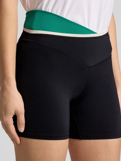 Frauenmodel trägt Slim Fit Shorts mit Logo-Detail Modell 'Status' von P.E Nation, Elastischer-Material-Mix, Nahaufnahme Oberkörper.