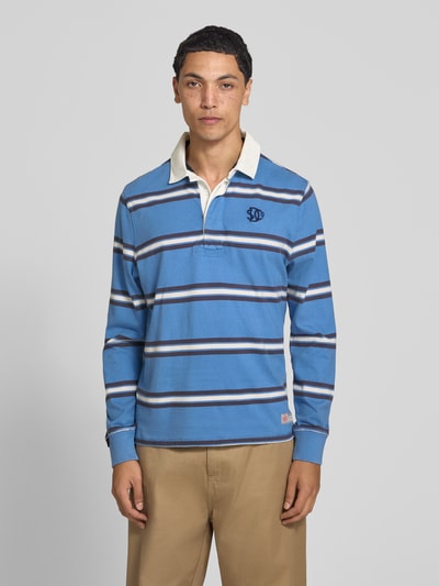 Männermodel trägt Poloshirt aus reiner Baumwolle von Superdry in Blau mit weißen und dunkelblauen Streifen, gerader Schnitt, Nahaufnahme Oberkörper. Rückenlänge bei Größe M 71 cm, Label-Stitching, elastische Abschlüsse, Polokragen mit Abdeckleiste.