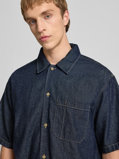 Mannelijk model draagt Relaxed Fit Jeanshemd met borstzak van Dickies in donkerblauwe katoen, kentkraag, knoopsluiting, label-patch, halfhoge mouwen, textuur met zichtbare stiksels, Nahaufnahme bovenlichaam.