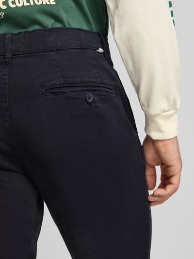 Męski model nosi Straight Fit Chino mit Eingrifftaschen Modell 'Vance' od Jack & Jones, mieszanka bawełny, ciemny kolor, wpuszczane i tylna kieszeń z guzikiem, zapięcie na guzik i zamek błyskawiczny, szerokość w rozmiarze 32/32: 43 cm, długość wewnętrzna nogawki: 67 cm, detal tylnej części spodni, zbliżenie na tył.