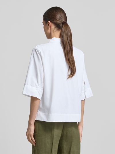 Modelka kobieca ma na sobie białą bluzkę koszulową Regular Fit Hemdbluse im Halbarm-Design model 'Netti' od Soyaconcept, mieszanka bawełny, krój regular fit, kołnierzyk koszulowy, rękaw o dł. 1/2, długość tyłu w rozmiarze S: 58 cm, długość rękawów w rozmiarze S: 37 cm, widok całej sylwetki od tyłu.