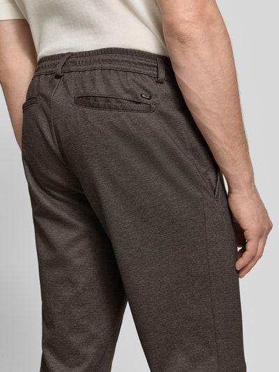 Männermodel trägt dunkelbraune Tapered Fit Jogpants mit Viskose-Anteil Modell 'Phil' von Brax, Herren Weite Hose, Nahaufnahme Rückansicht.