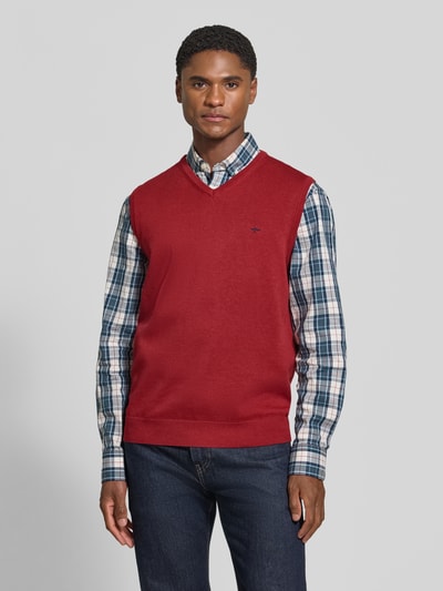 Männermodel trägt Regular Fit Pullunder aus reiner Baumwolle mit Logo-Stickerei von Fynch-Hatton, rote Farbe, V-Ausschnitt, Ganzkörperansicht von vorne. Rückenlänge bei Größe M: 72 cm, gerippte Bündchen.