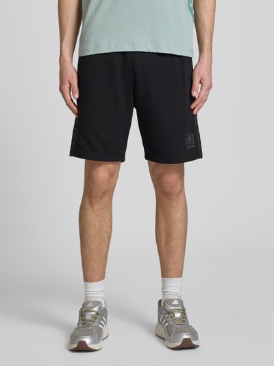 Männermodel trägt schwarze Shorts mit Logo und elastischem Bund von CHAMPION, Baumwoll-Mix, Regular Fit, Ganzkörperansicht von vorne