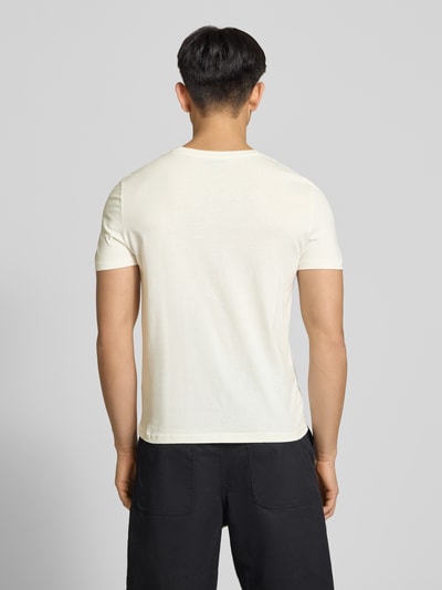 Männermodel trägt Basic Slim Fit T-Shirt mit Flock-Logo auf der Brust von REVIEW aus Baumwoll-Viskose-Mix in Creme, Rückenlänge 64 cm, Ganzkörperansicht Rückansicht.