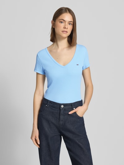 Vrouwenmodel draagt Slim Fit T-shirt uit katoenmix van Tommy Jeans in effen kleuren met gestikt logo, ronde hals en korte mouw, jersey materiaal, vooraanzicht bovenlichaam.