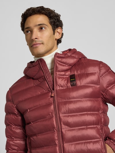 Männermodel trägt Steppjacke mit Zweiwege-Reißverschluss Modell 'CHARLES' von Blauer USA in Rot, glatte Textur, Nahaufnahme Oberkörper.