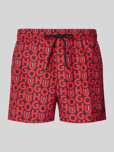 Produktfoto, Badeshorts mit Allover-Muster Modell 'NALU' von HUGO in Rot mit schwarzem Label-Schriftzug, elastischer Bund, seitliche Taschen