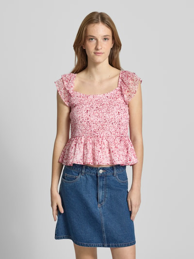 Frauenmodel trägt Slim Fit Blusentop mit Allover-Muster Modell 'ELIZA' von Only in floraler Optik aus Chiffon, Volants, Henley-Ausschnitt, Farben Rosa und Weiß, strukturierte und leichte Textur, Ganzkörperansicht von vorne.
