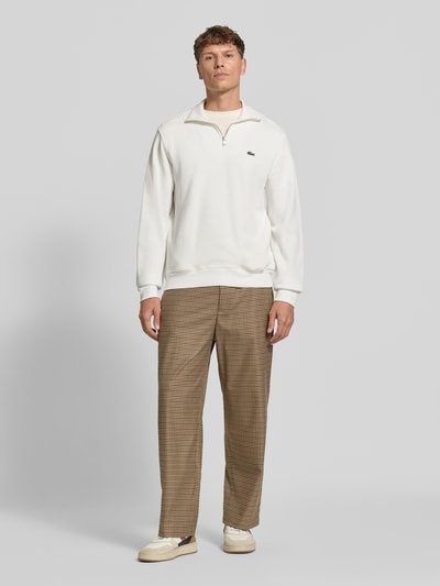 Männermodel trägt Regular Fit Troyer aus reiner Baumwolle von Lacoste in Weiß mit glatter Textur, Ganzkörperansicht von vorne. Herren Troyer von Lacoste.