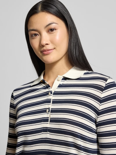 Frauenmodel trägt Regular Fit Poloshirt mit Streifenmuster von Gant in Dunkelblau und Creme, Baumwoll-Modal-Mix, Nahaufnahme Oberkörper.