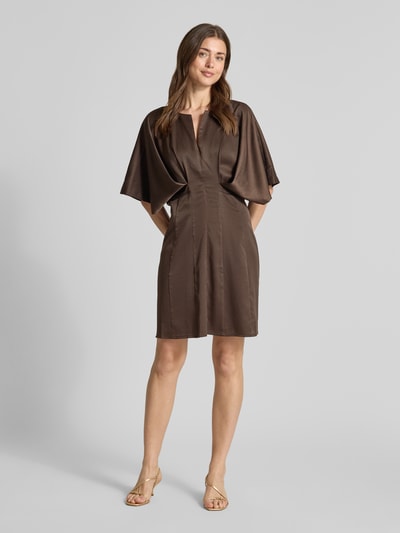 Frauenmodel trägt knielanges Kleid mit Viskose-Anteil Modell 'VIANNA' von Copenhagen Muse in Braun, Satin mit 3/4-Arm, taillierte Passform, Ganzkörperansicht von vorne.