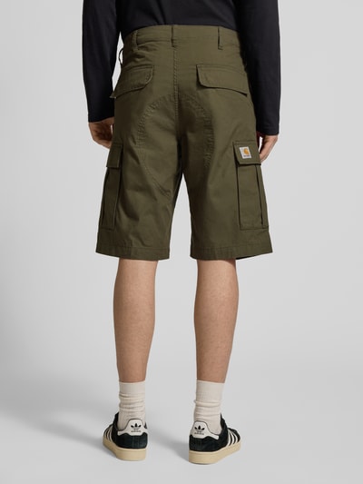 Männermodel trägt olivgrüne Shorts mit Cargotaschen von Carhartt Work In Progress, Regular Fit, Gesäßtaschen, Ganzkörperansicht Rückansicht.