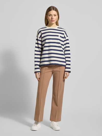Frauenmodel trägt Stoffhose mit elastischem Bund Modell 'RENEE' von Raffaello Rossi in Beige, Material-Mix mit Stretch-Anteil, Gerader-Schnitt, Bundfalten, Französische-Eingrifftaschen, Gesäßtaschen, Ganzkörperansicht von vorne.