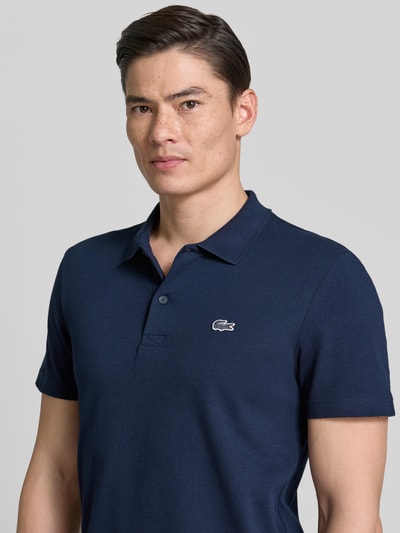 Männermodel trägt Regular Fit Poloshirt aus Baumwoll-Mix von Lacoste, Optik: Unifarben, Logo-Patch, Polokragen, Kurzarm, Nahaufnahme Oberkörper.